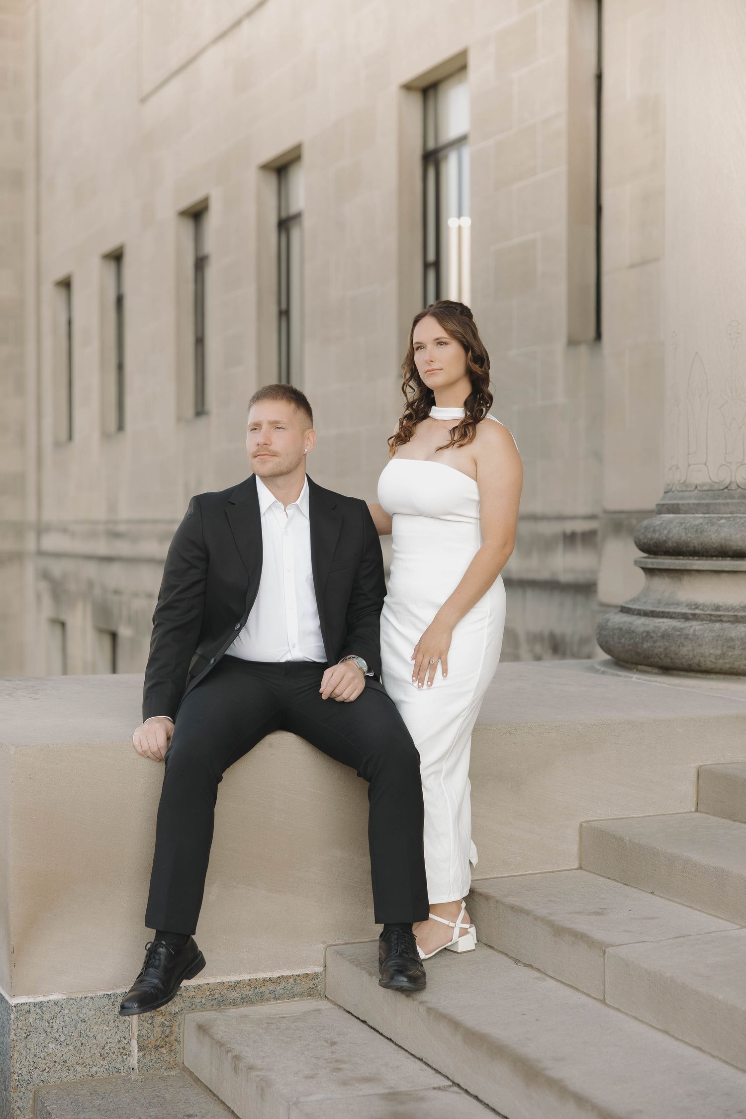 A series of romantic wedding poses on stone steps features a couple in black and white attire against an elegant building.