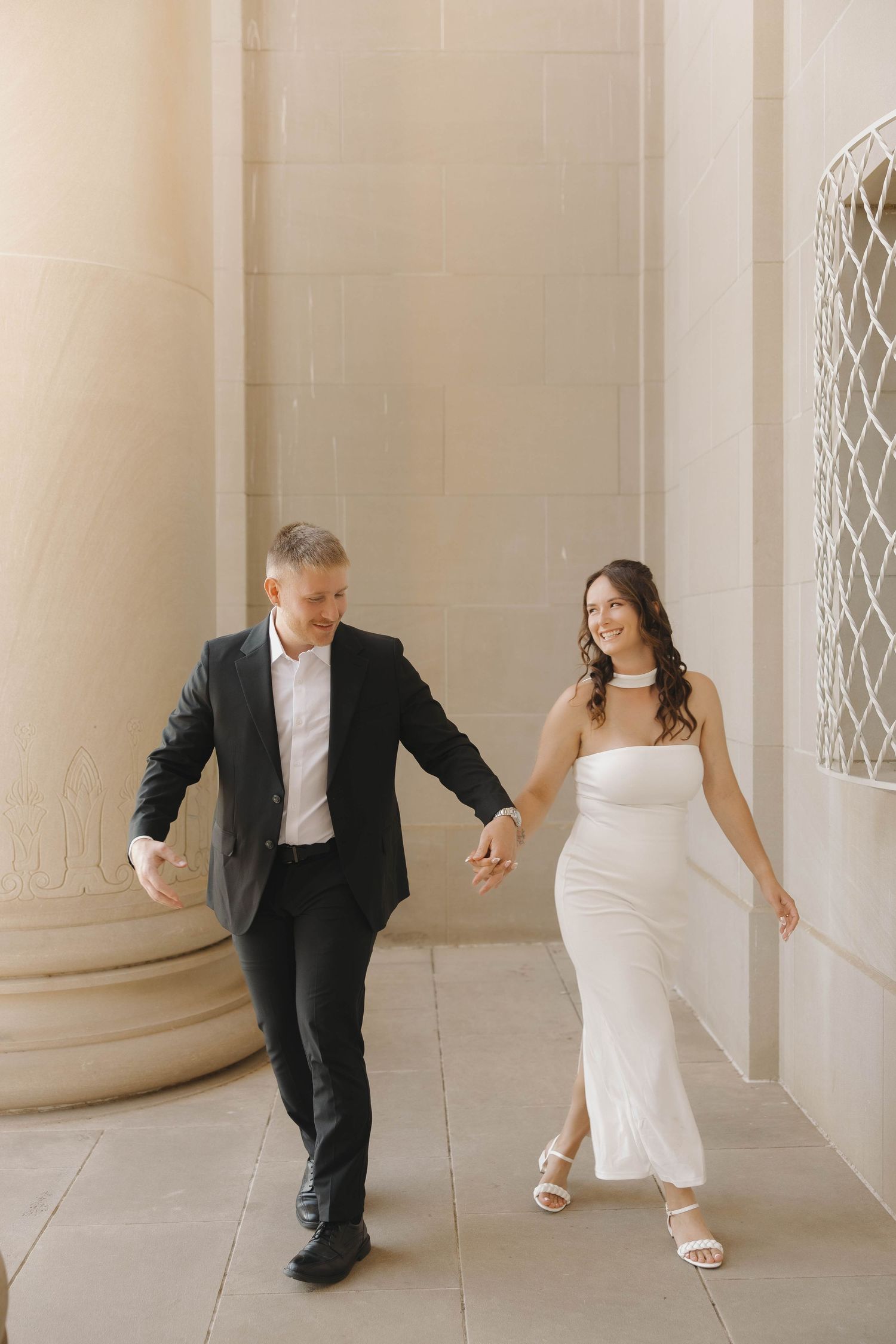 A sequence of playful wedding photos showing a couple dancing behind columns in a light stone hallway.