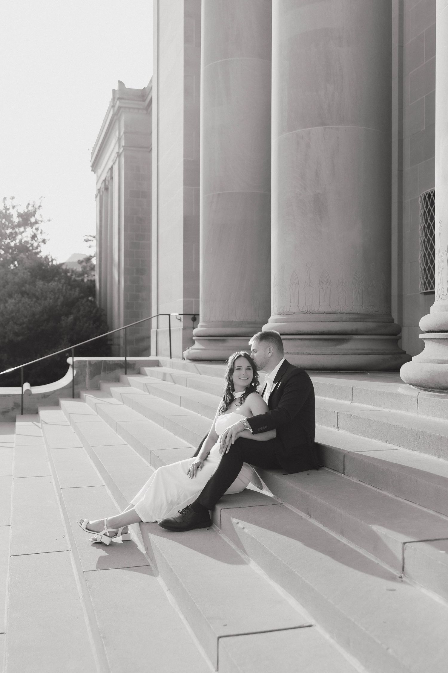 A romantic engagement photo session inside a classical building with grand columns and dramatic lighting effects.
