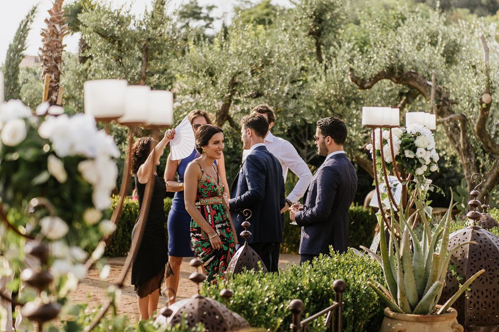 Outdoor wedding ceremony setup with guests seated among lush Mediterranean garden scenery.