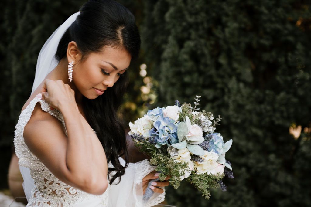 Elegant bridal portrait showing delicate white dress details and floral bouquet in natural lighting.