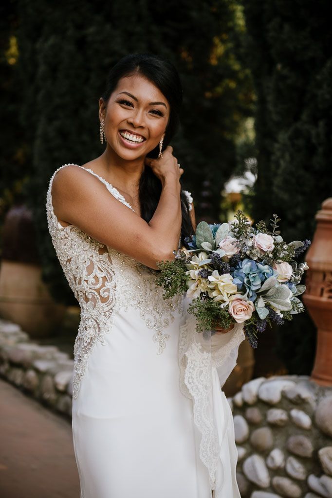 Delicate bouquet of blue and white flowers complements a lace wedding gown.