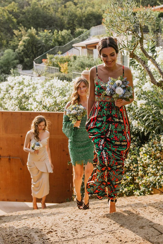 Guests in colorful summer dresses walking through a sunny garden path.