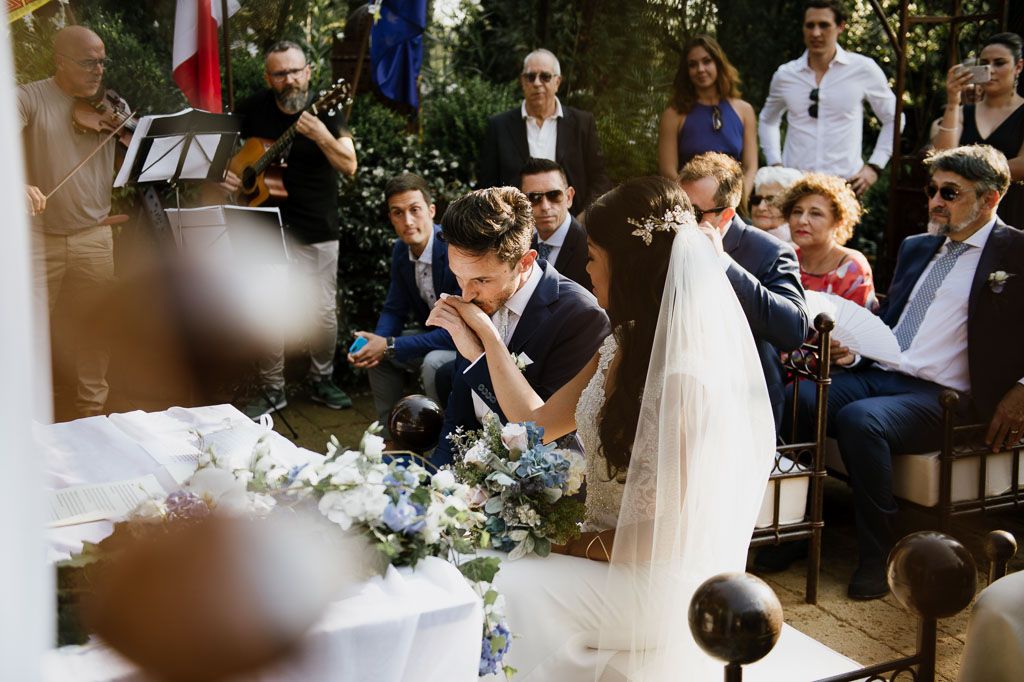 Wedding ceremony outdoors with guests seated and floral decorations on display.