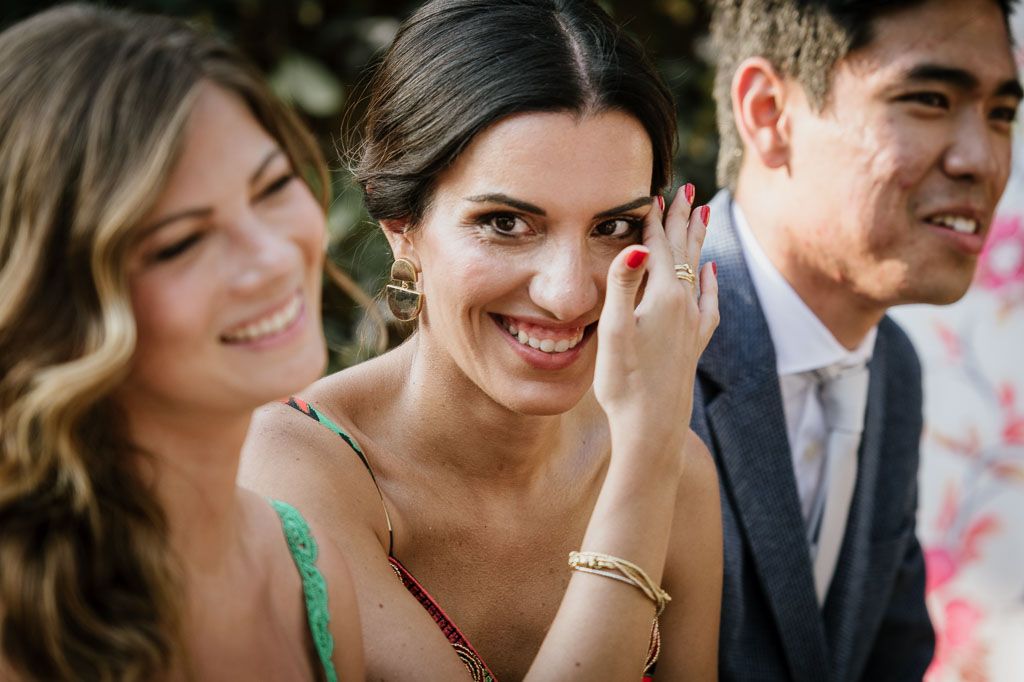 Joyful candid moments captured between wedding attendees during outdoor celebration.