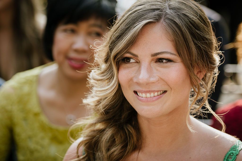 Close up portrait of someone in soft natural lighting with a warm smile and wavy brunette hair.