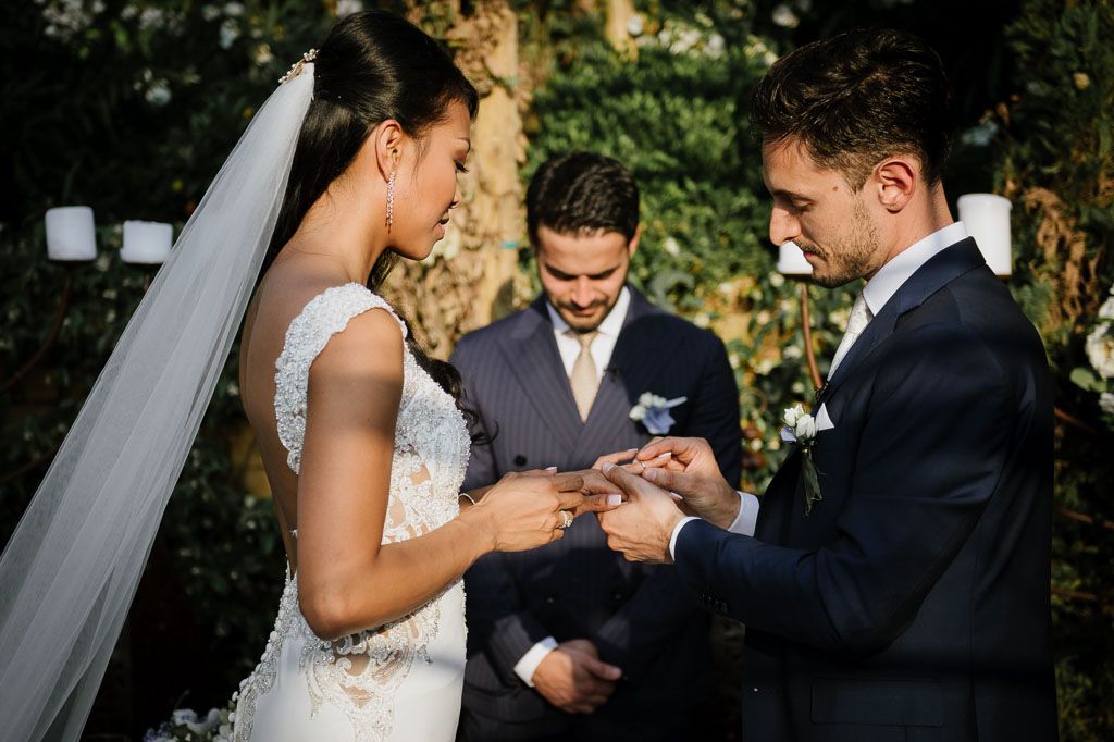 Wedding ceremony moment during ring exchange at outdoor venue.