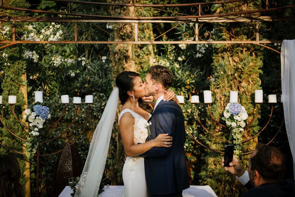 A romantic outdoor wedding ceremony under string lights and greenery.