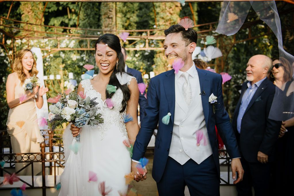Joyful wedding celebration with confetti as couple exits ceremony under natural lighting.