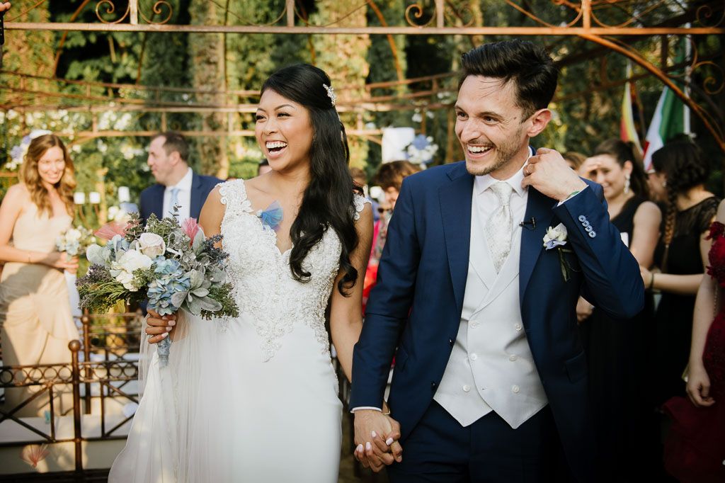 Newlyweds laughing together during their wedding ceremony surrounded by guests.