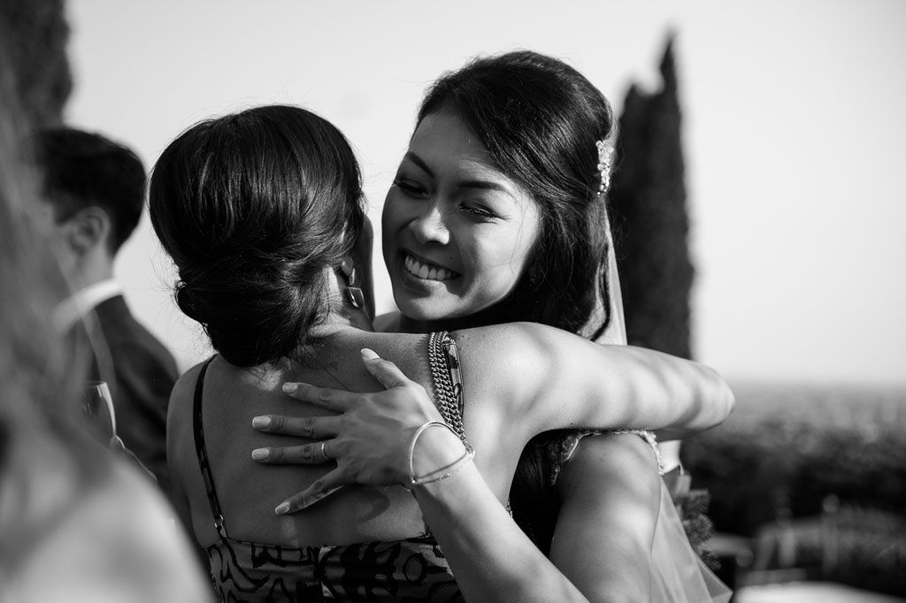 Black and white portrait of two wedding guests sharing an emotional embrace.