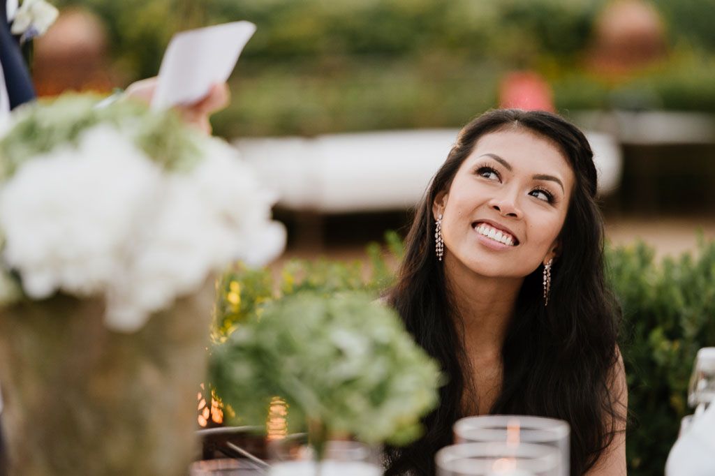 Wedding guest smiling warmly while listening to reception speeches.