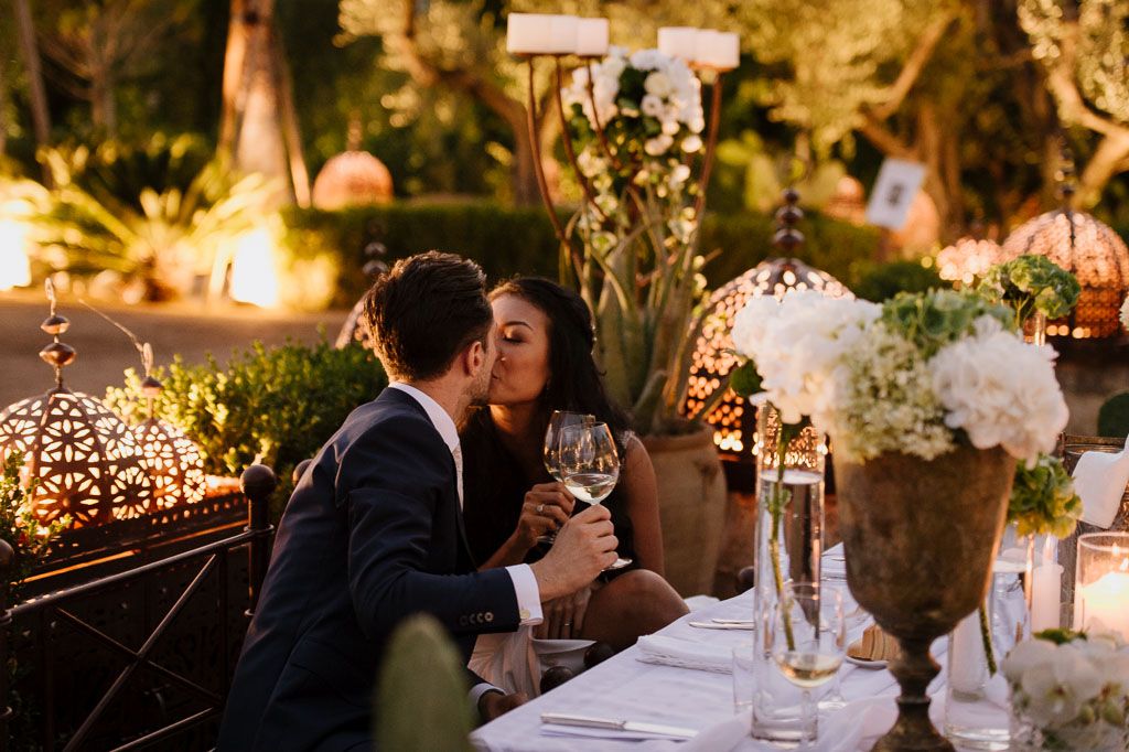 Romantic evening reception scene with couple at candlelit table surrounded by ambient lighting.