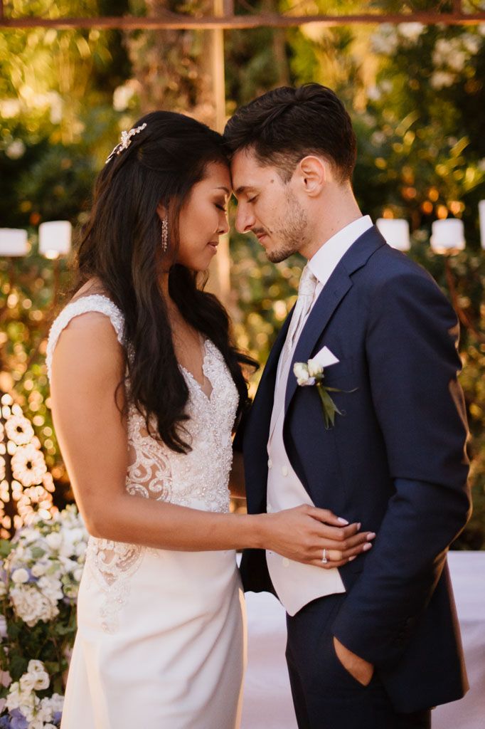 Intimate moment between newlyweds against golden sunset backdrop with floral decorations.