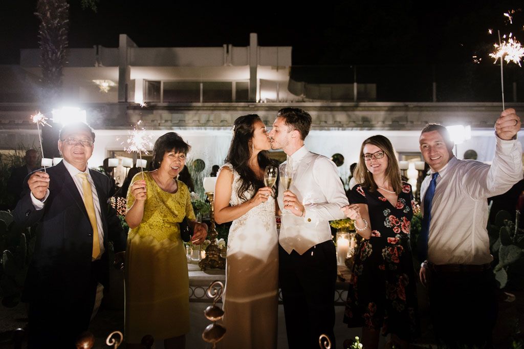 Wedding reception celebration at night with sparklers and guests gathered around.