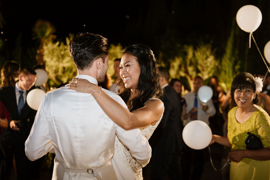 Glowing paper lanterns illuminate an outdoor evening wedding celebration.
