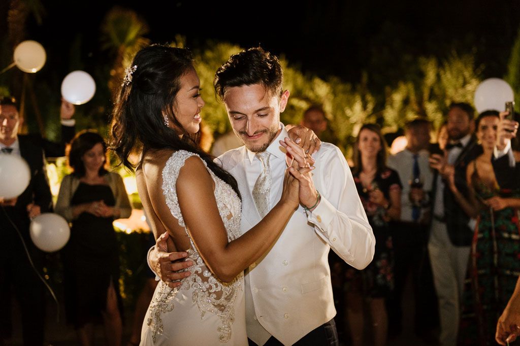 Romantic evening wedding reception with dancing under string lights and lanterns.