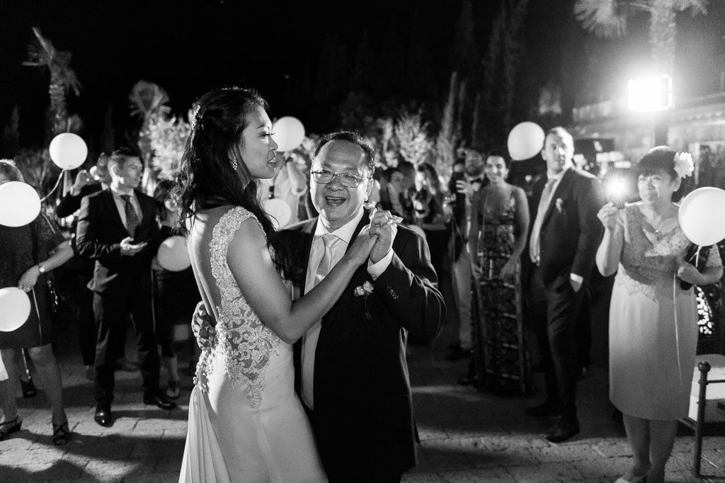Wedding guests dance enthusiastically on the nighttime dance floor during a lively reception celebration.