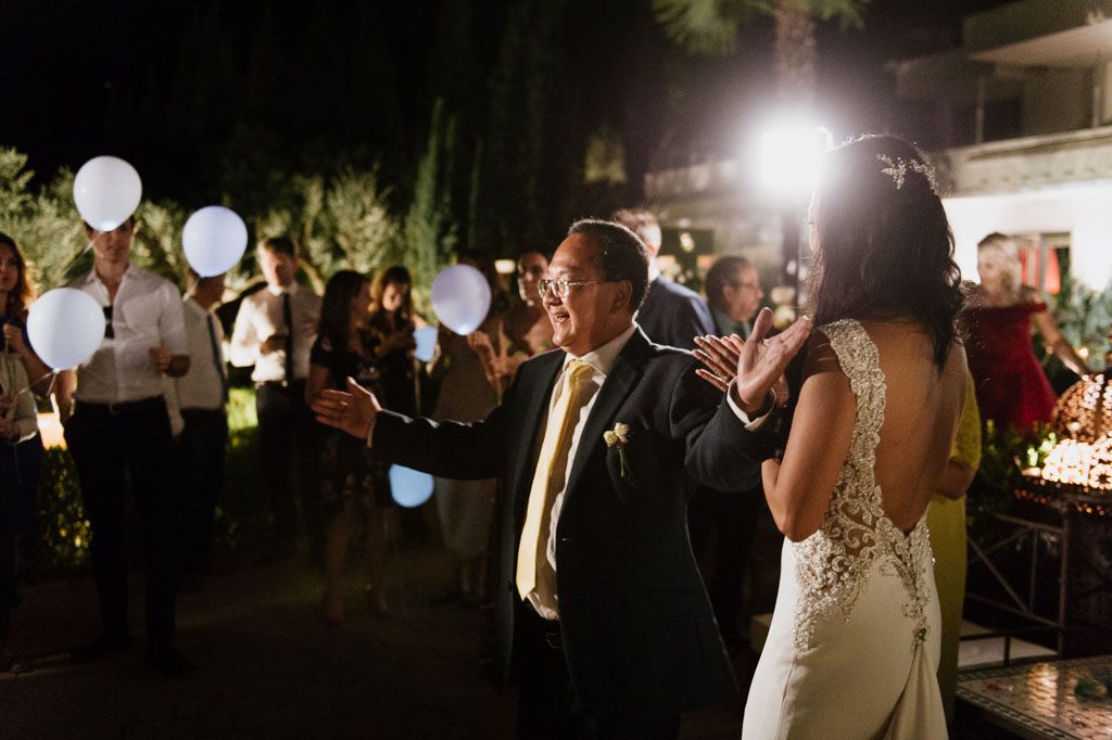 Couples dance together under white balloons at an elegant outdoor evening wedding reception.