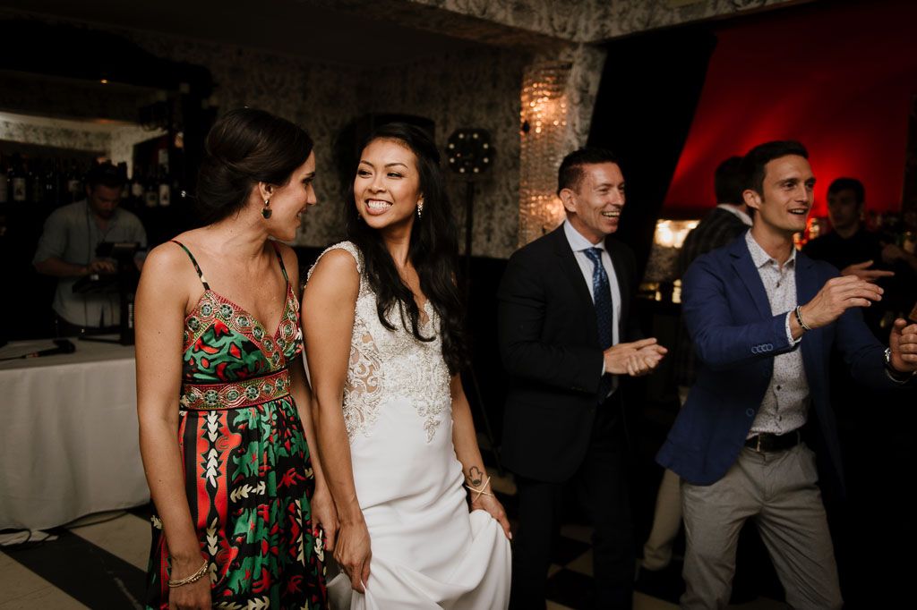 Wedding guests dance and celebrate together on a checkered dance floor at an evening reception.