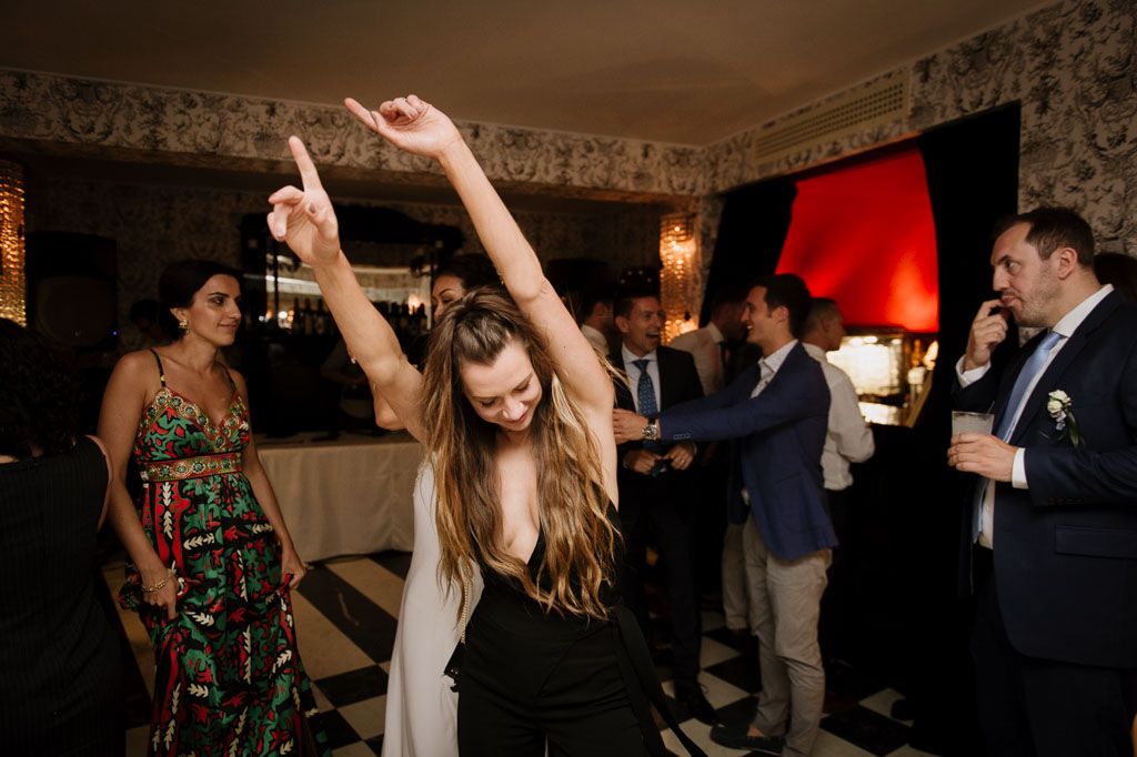 Guests enjoy dancing and mingling at an elegant indoor wedding reception with ornate decor.