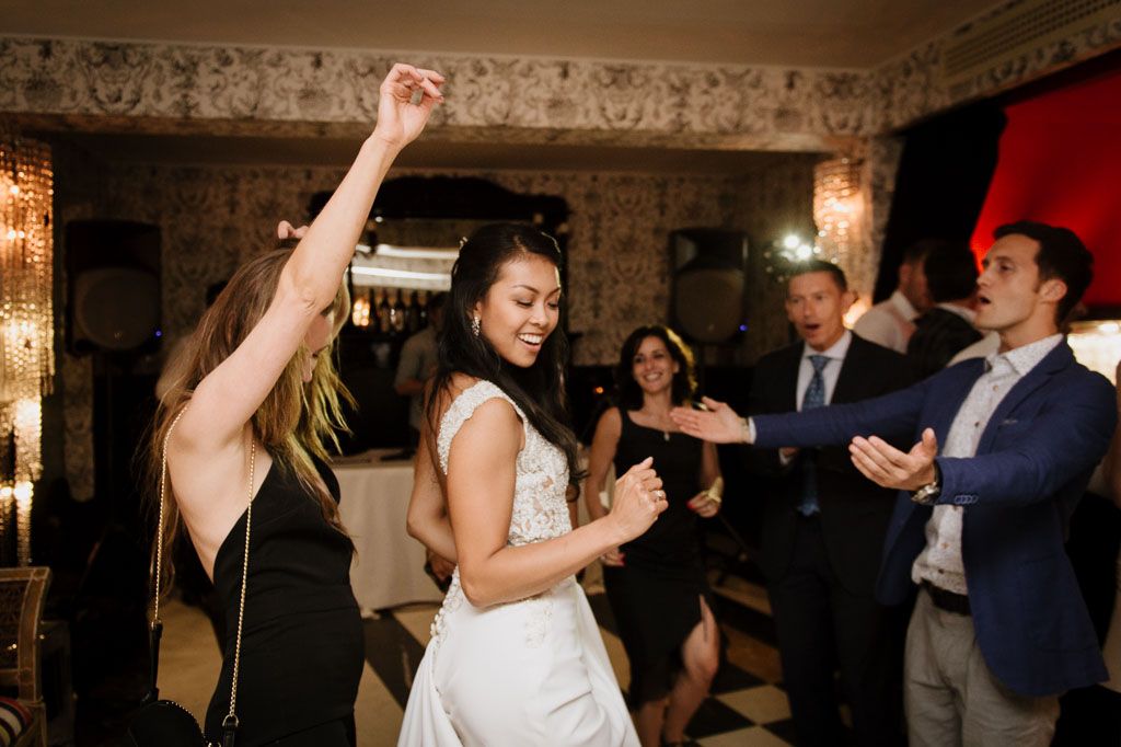 Couples dancing together at an elegant wedding reception in a ballroom with ornate crown molding and chandeliers.