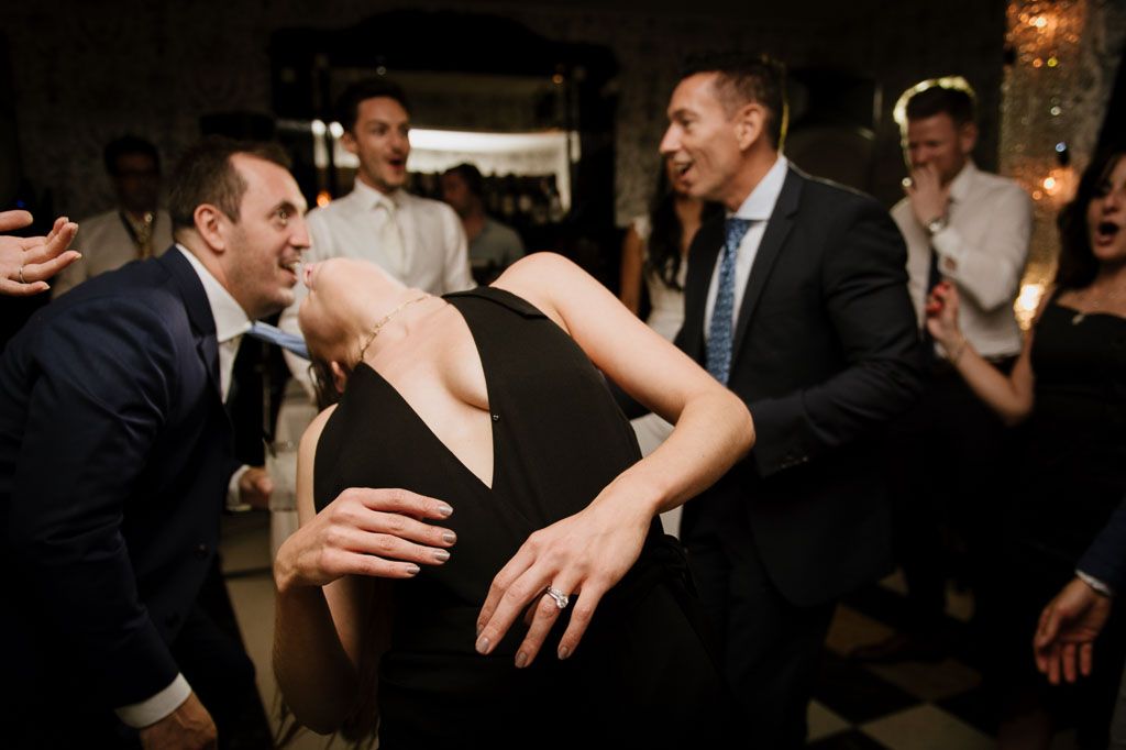 People dancing and celebrating at a dimly lit evening wedding reception.