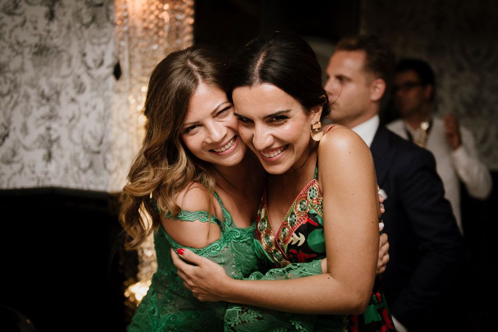 Two guests in emerald green dresses share a joyful moment on the dance floor.