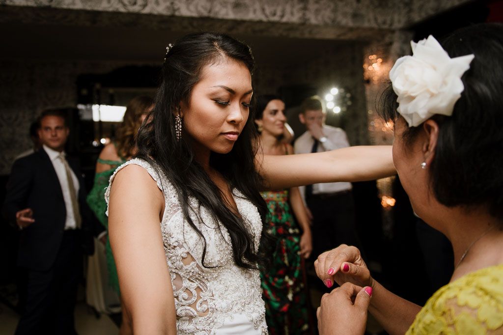 People dancing and moving energetically at a wedding party with warm lighting and decorative ceiling.