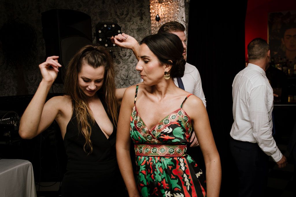 Partygoers in colorful attire dance and celebrate at a festive evening event.