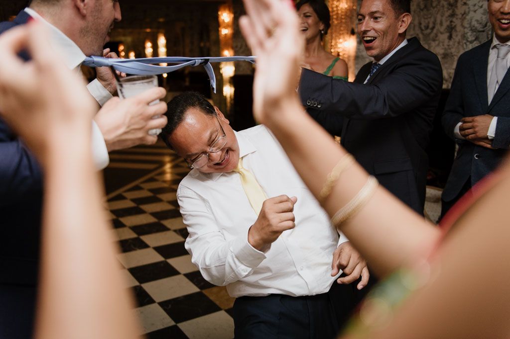 Guests celebrate on a black and white checkered dance floor at an indoor wedding reception.