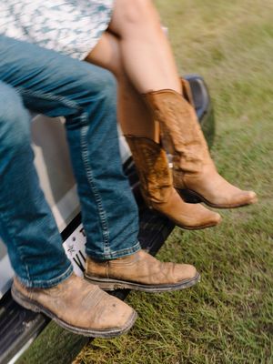 Close-up sequence of brown leather boots with blue jeans stepping on grass showing walking motion.