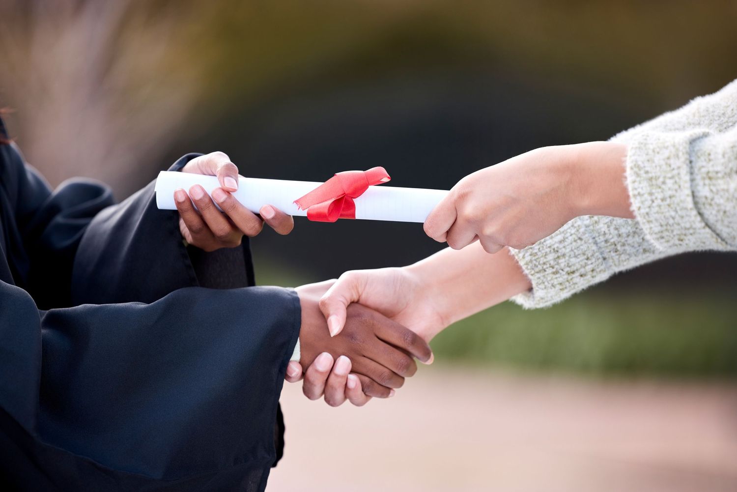 Close-up view of two hands exchanging car keys over a black surface in natural lighting.