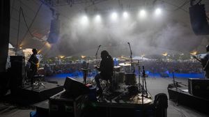 Panoramic view of a concert stage with dramatic fog and bright spotlights.