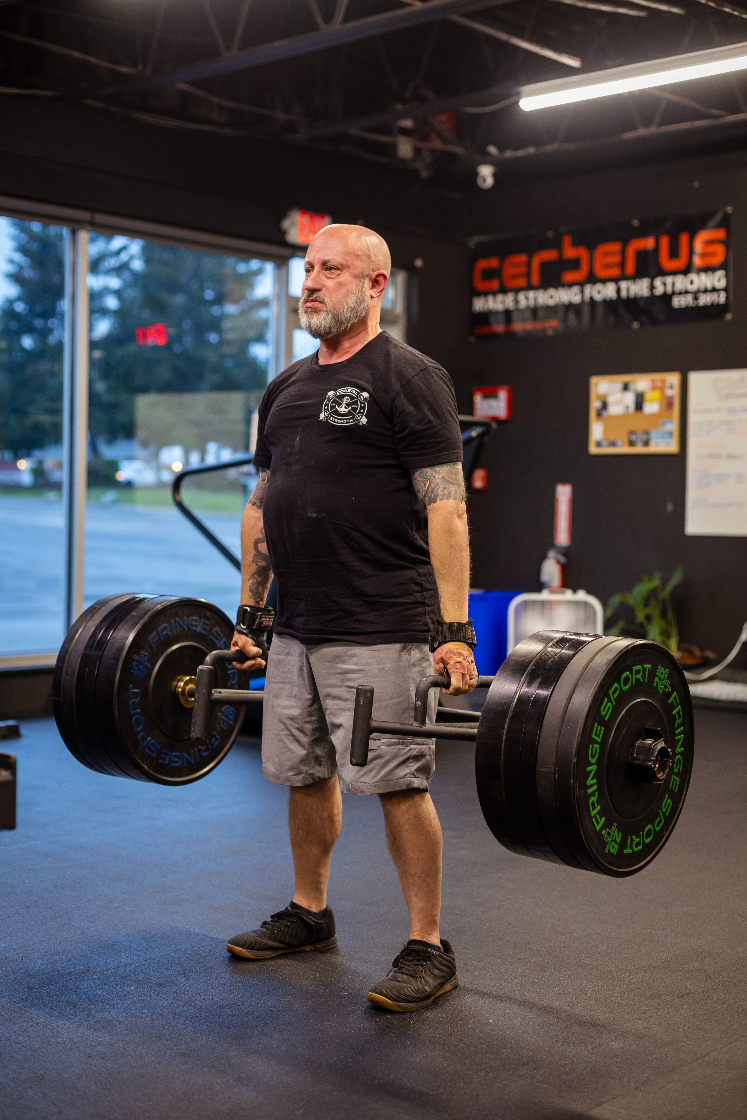 Strongman lifting heavy barbell during workout at Cerberus gym.