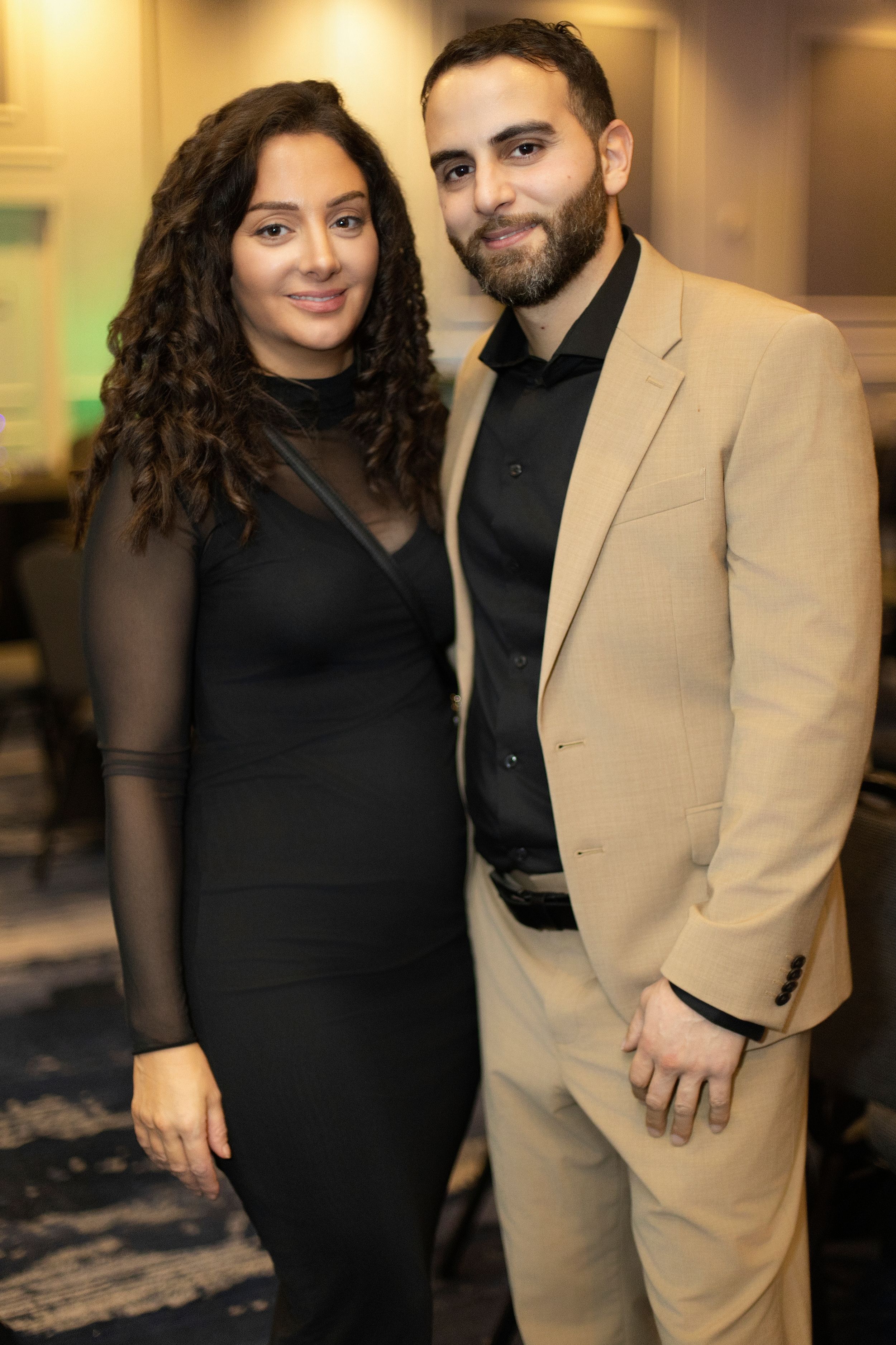 A couple in formal attire poses together at an indoor event.