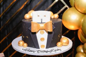 Close-up of an elegant black and gold birthday cake with decorative elements.