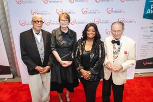 Group photo of attendees posing on red carpet at an awards event.