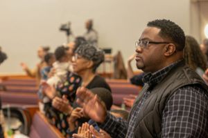 Audience members seated in church pews listening attentively to presentation.