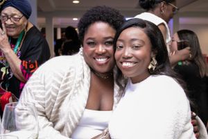 People gather together at a social celebration with warm lighting and joyful expressions.