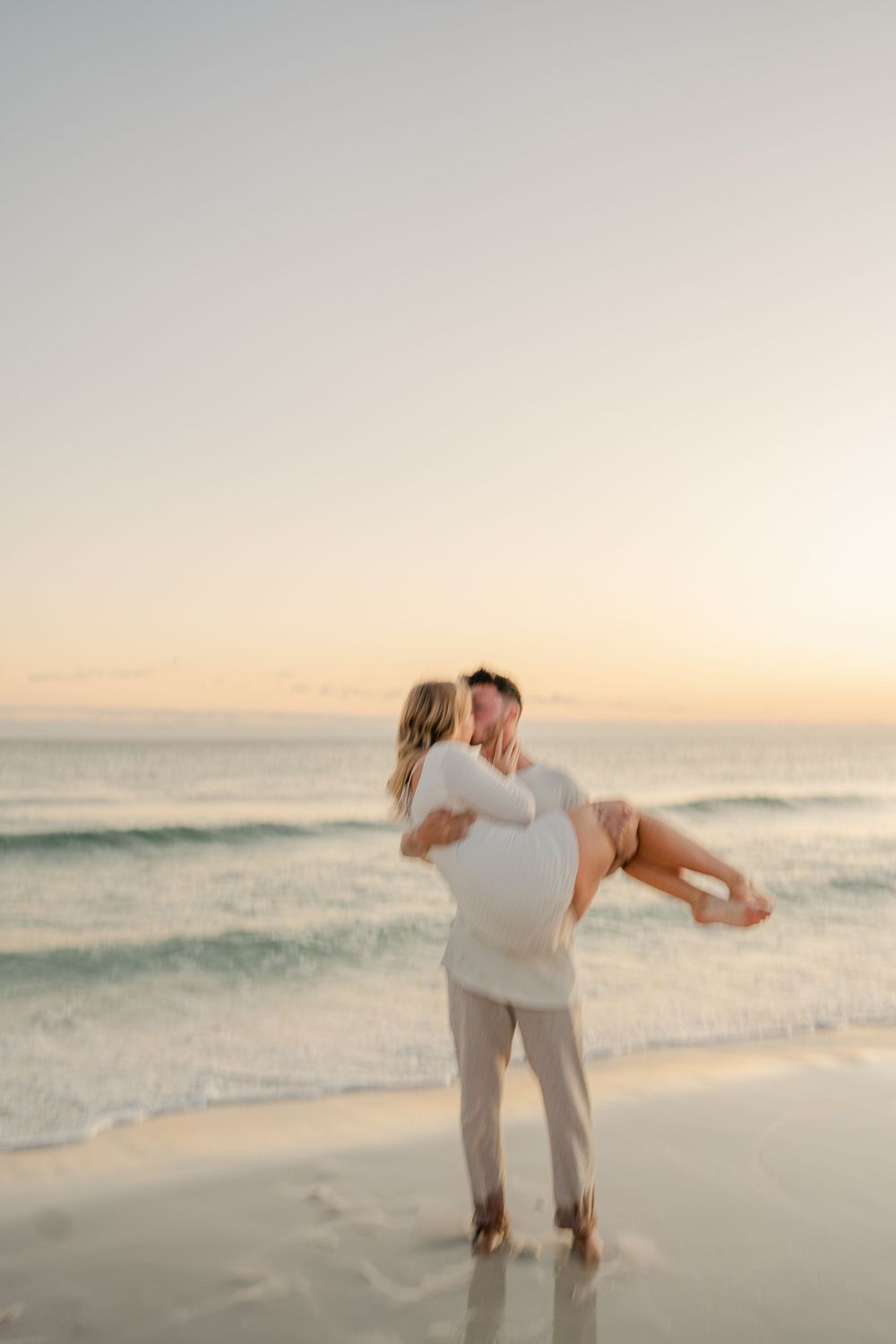 Playful couple moment captured during sunset beach photoshoot.