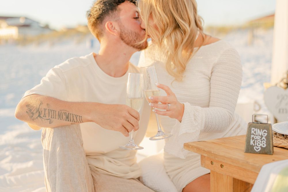 A romantic moment shared under a beach canopy with champagne at sunset.