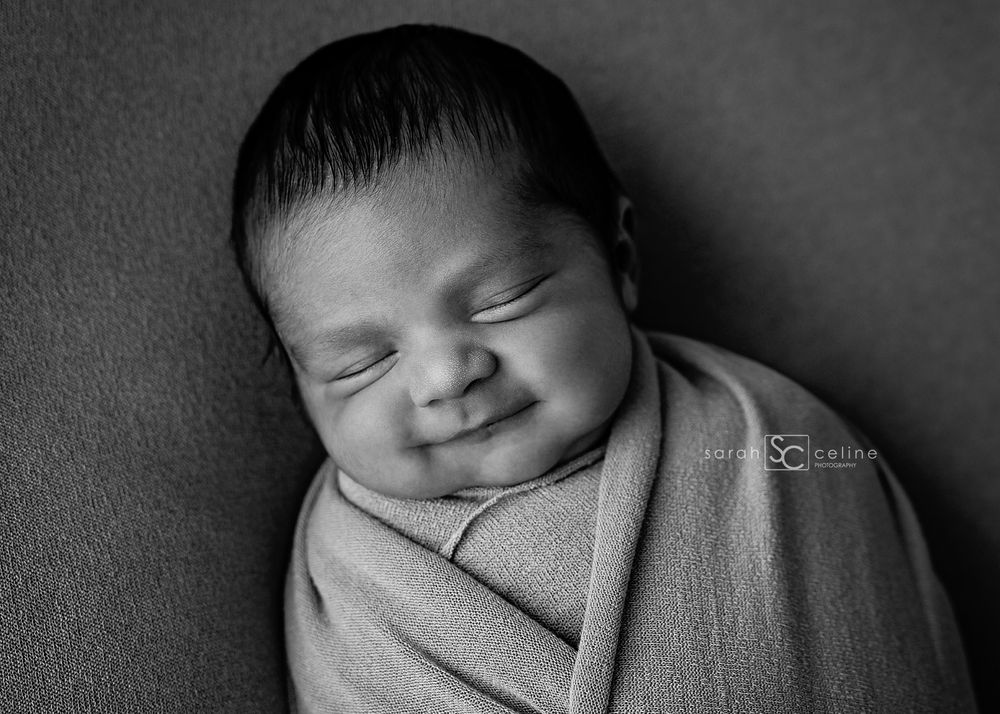 Black and white portrait series showing peaceful newborn sleeping in soft swaddle wrap.