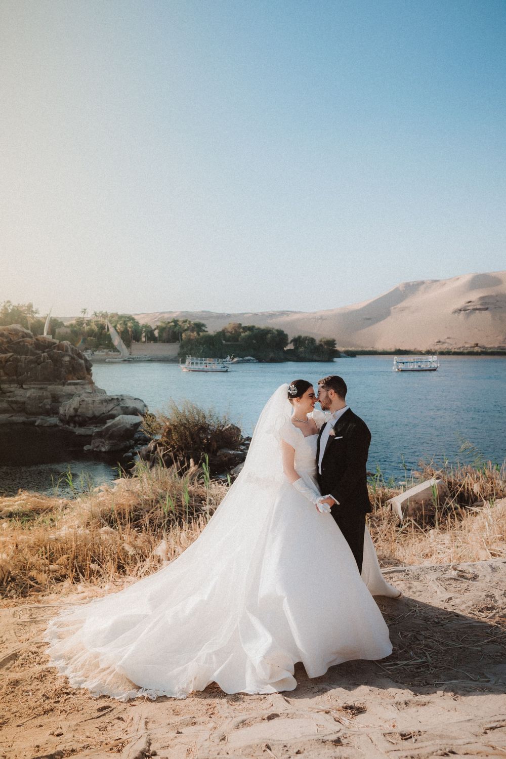 A romantic wedding portrait captured against a scenic desert lake backdrop.