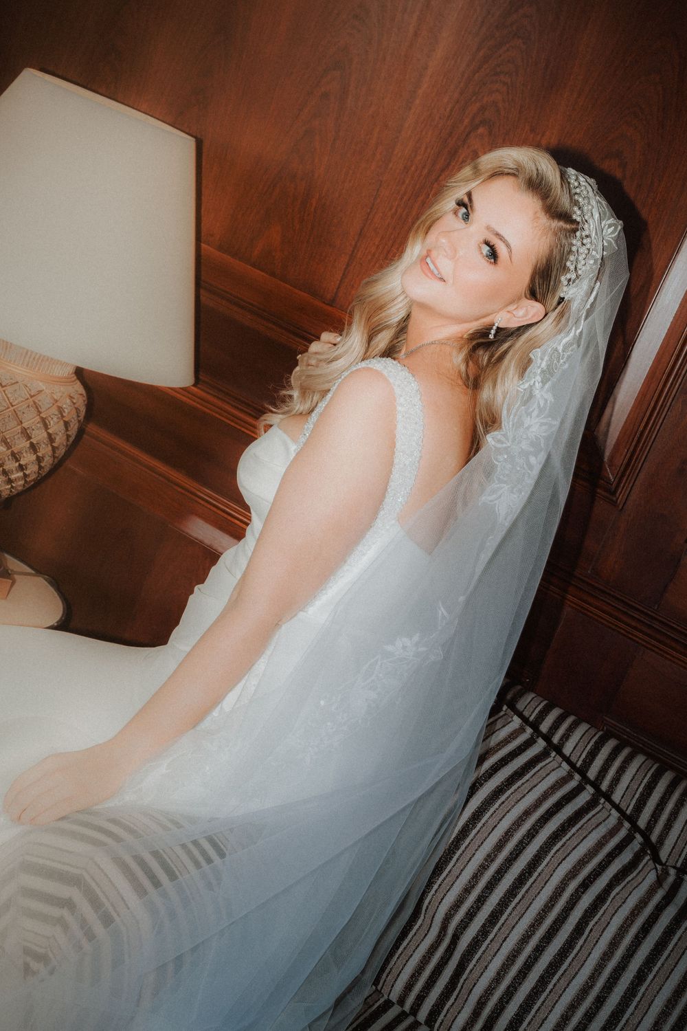Dreamy boudoir style bridal portrait in white gown against wood paneled interior.