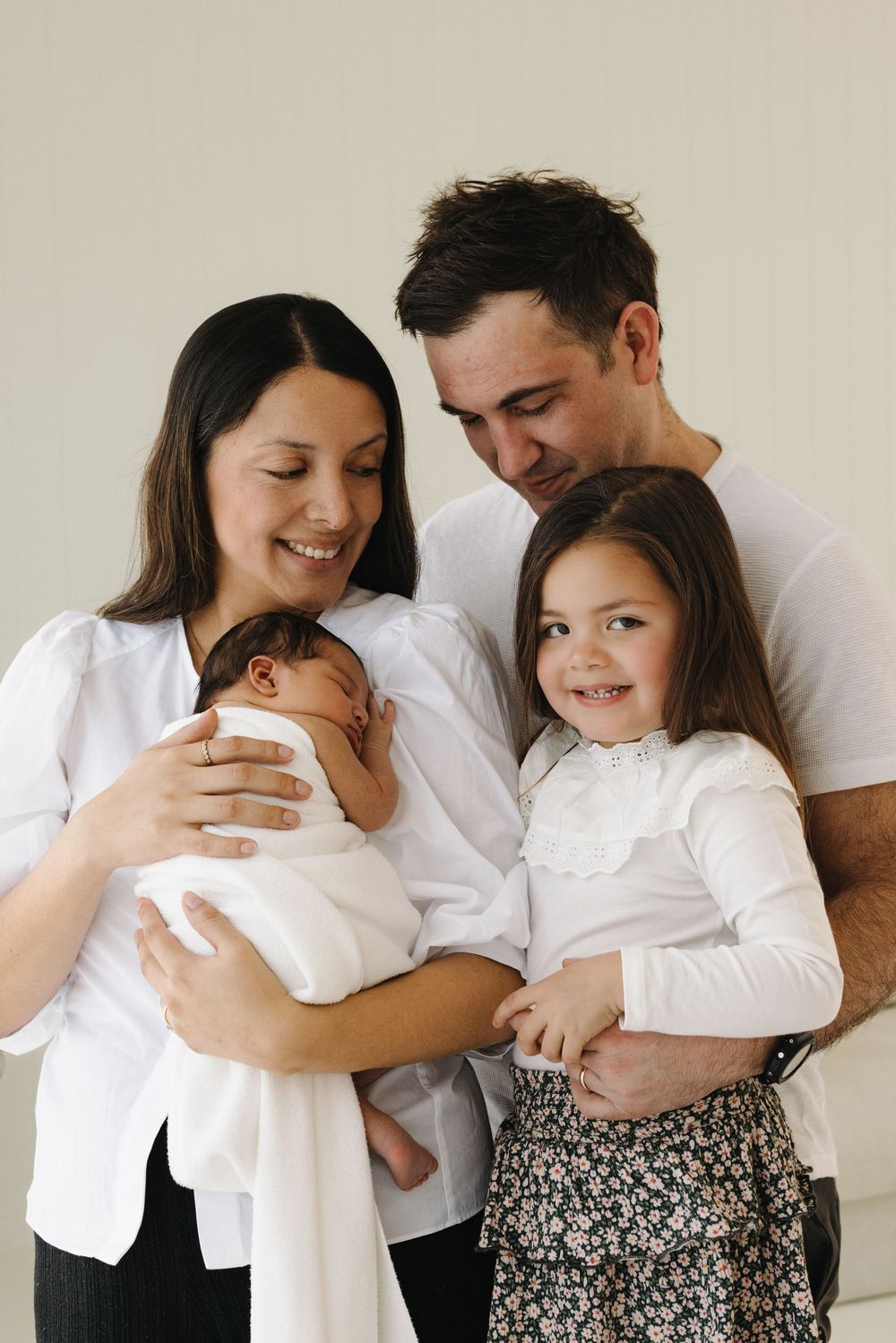 A family shares tender moments together in a series of casual lifestyle photos wearing white and floral clothing.