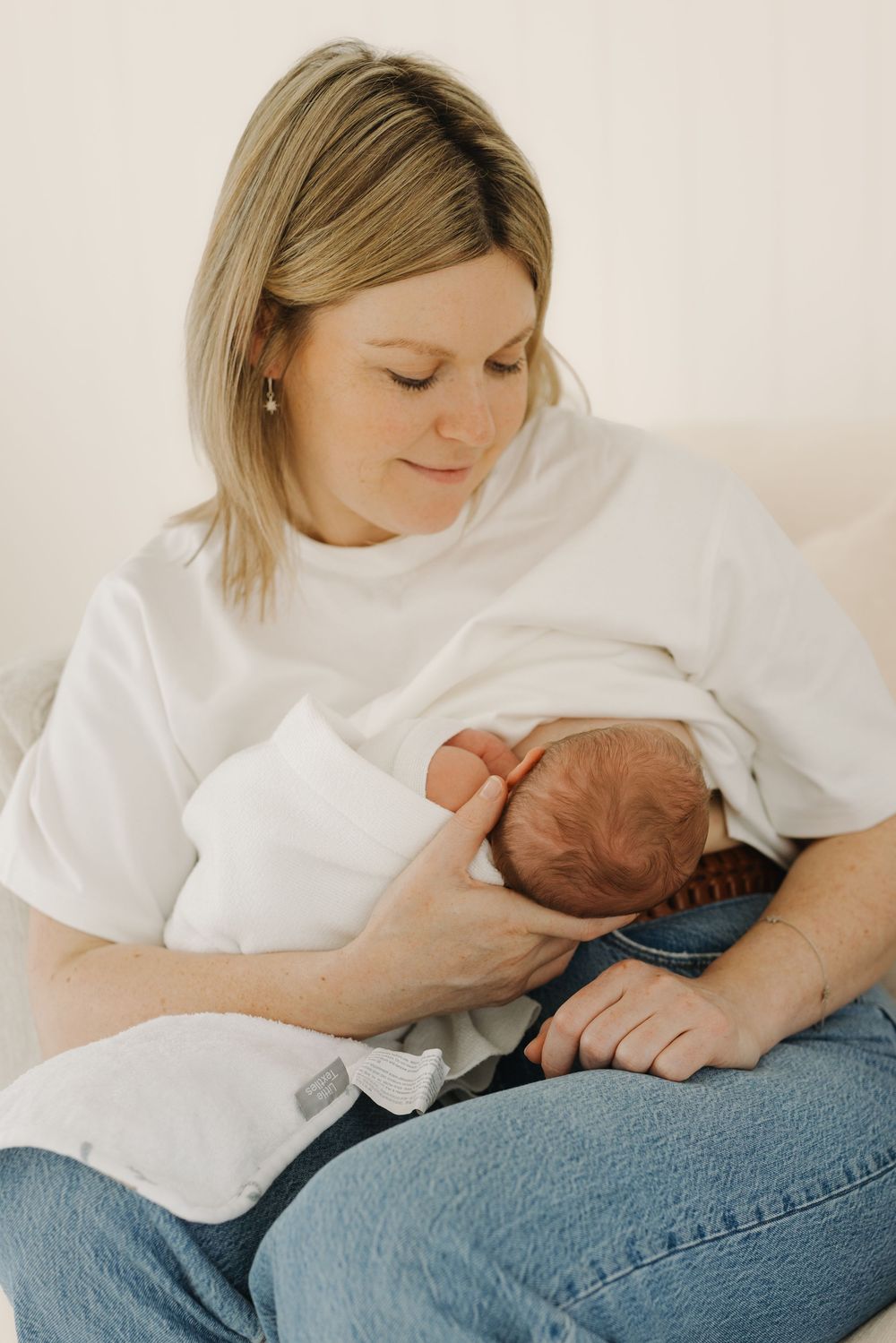A series of intimate photos showing a parent in white top and jeans holding and bonding with a newborn baby.