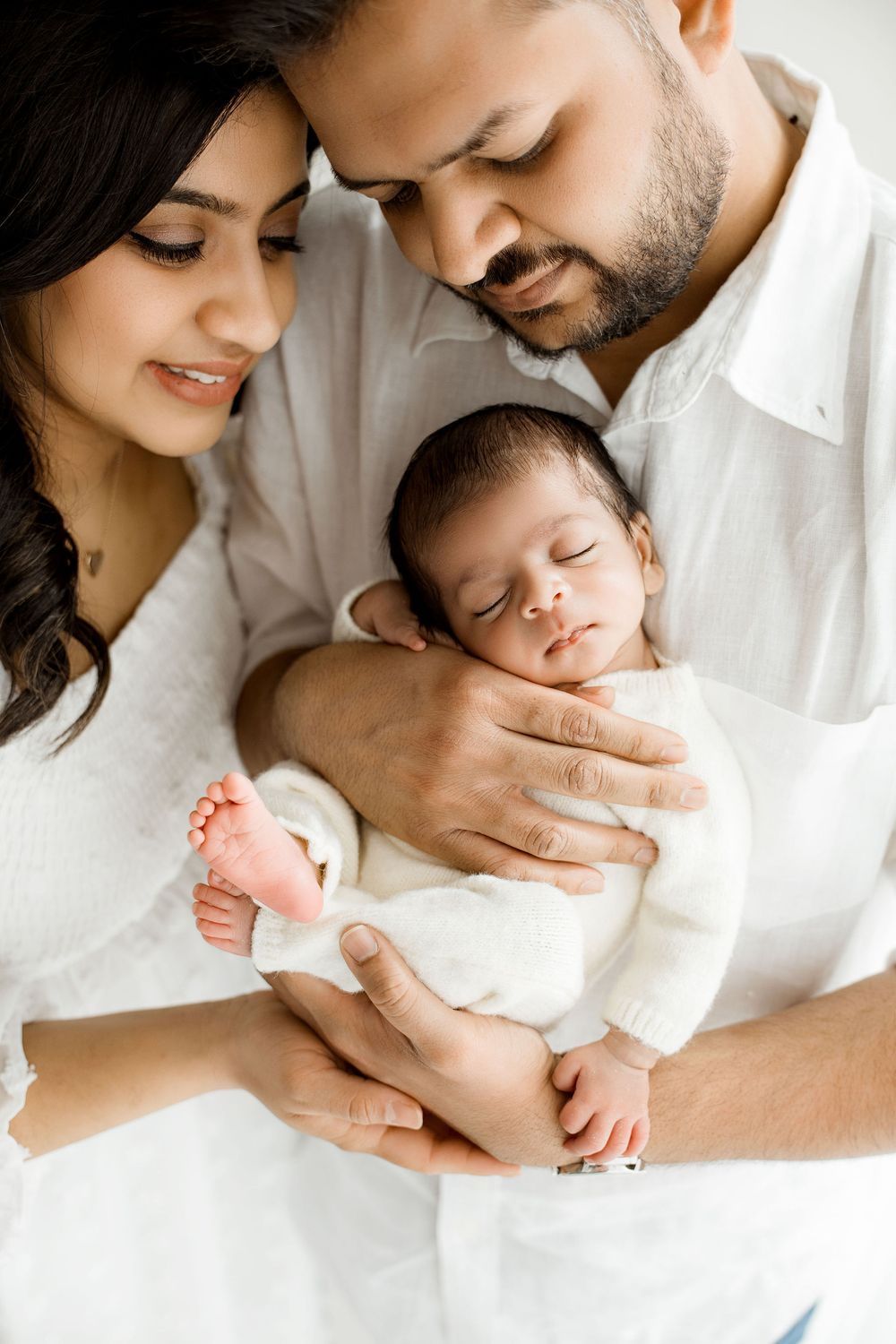 Baby newborn boy in parents hands, both parents looking at the baby