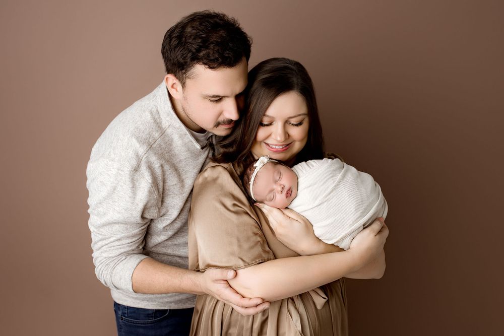 Family of three, mom and dad looking at the newborn baby girl