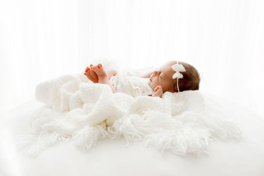 Newborn session with baby by the window, laid on a white cozy blanket. Studio located in Algonquin IL